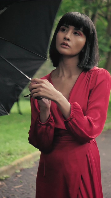 少妇在打开她的伞的公园掩盖自己从雨