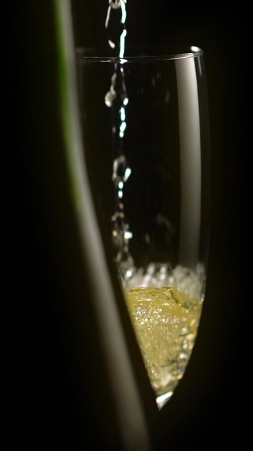 香槟倒入玻璃酒杯在深色背景上