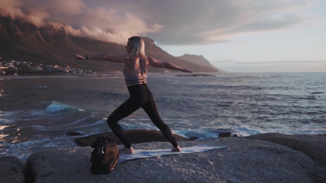 在海边石头上做瑜伽的女人